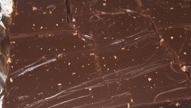 Rich and creamy old fashioned chocolate fudge cut into perfect squares on a rustic wooden board, with a dusting of cocoa powder and a vintage spatula on the side, evoking a nostalgic and indulgent treat