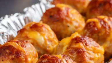 A platter of golden-brown sausage balls fresh out of the oven, served on a rustic wooden table, ready to be enjoyed at a festive gathering