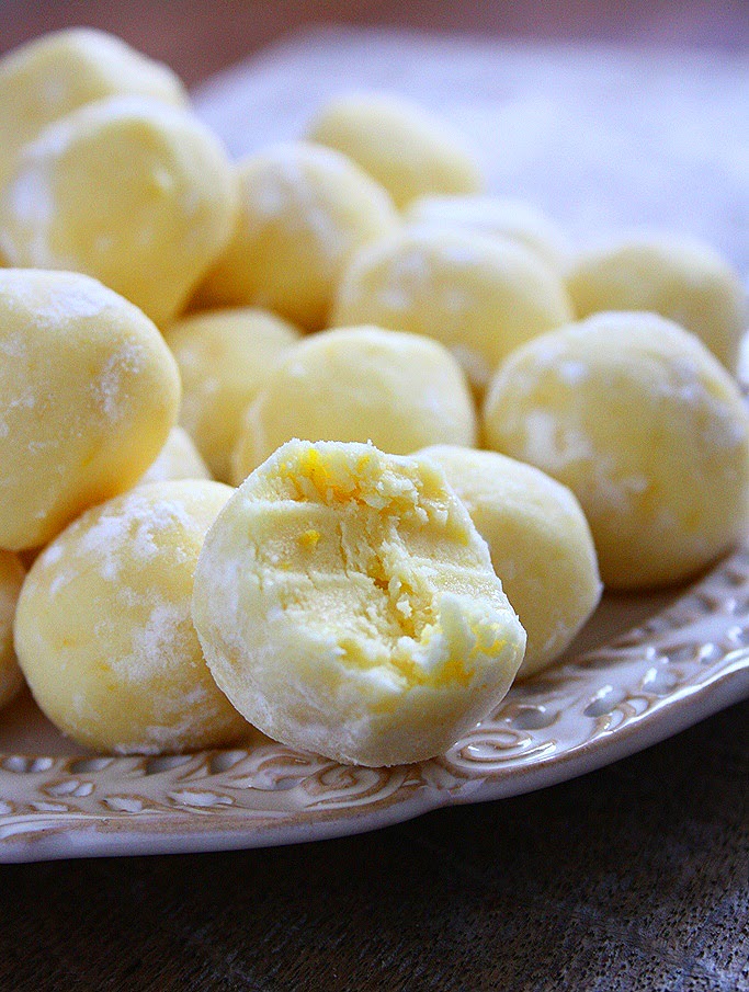 Delicious lemon truffles coated in powdered sugar and garnished with lemon zest, displayed on a white plate