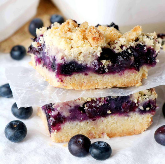 Freshly baked Blueberry Buckle in a rustic kitchen setting, topped with a golden brown sugar crust and served with a scoop of vanilla ice cream, creating an inviting and traditional dessert experience