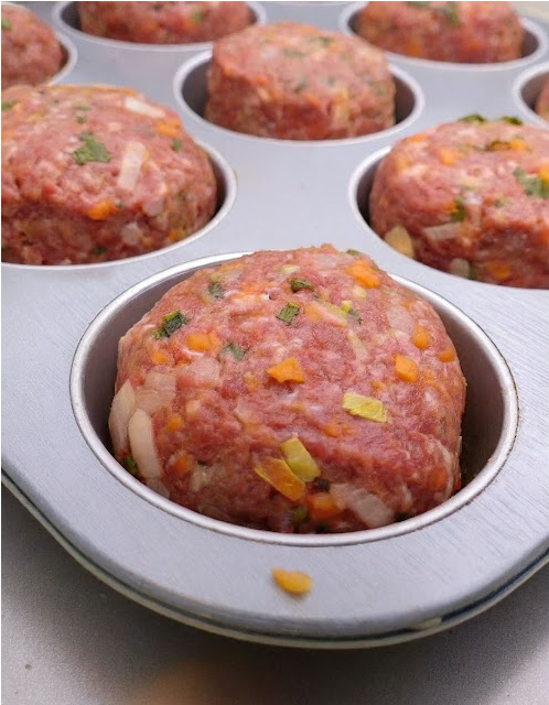 Freshly baked mini meatloaf muffins topped with a dollop of ketchup, arranged beautifully on a rustic wooden serving tray, complemented with a side of green beans and mashed potatoes, perfect for a family dinner