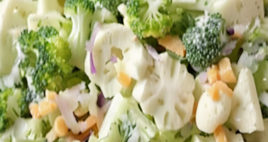 A colorful and refreshing broccoli and cauliflower salad in a large serving bowl, garnished with crispy bacon and shredded cheddar cheese, ready to be served at a family gathering or outdoor picnic