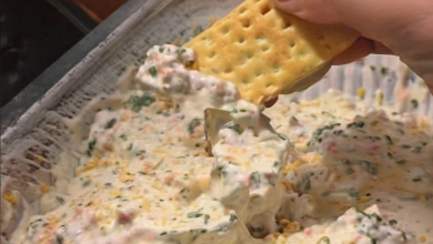 Close-up view of a creamy, textured dip in a serving bowl, surrounded by an assortment of dipping options like chips, sliced bread, and fresh veggies, ready to be enjoyed at a casual gathering