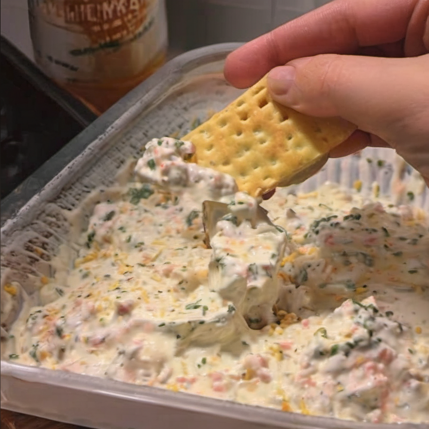 Close-up view of a creamy, textured dip in a serving bowl, surrounded by an assortment of dipping options like chips, sliced bread, and fresh veggies, ready to be enjoyed at a casual gathering
