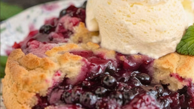 A freshly baked blackberry cobbler, featuring a golden, crispy crust and juicy blackberries, served warm with a dollop of whipped cream