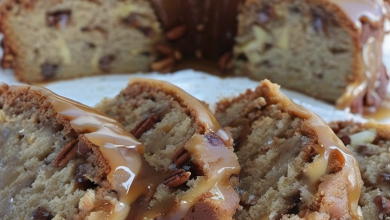 Freshly baked apple pecan cake on a rustic table, generously topped with a glossy caramel glaze, surrounded by autumn leaves.