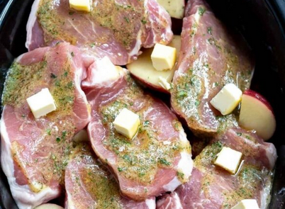 Succulent ranch-seasoned pork chops and tender red potatoes cooked in a crockpot, garnished with fresh parsley.