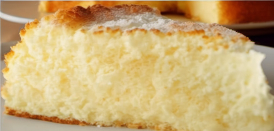 Freshly baked Fluffy Cloud Cake in a round pan, cooling on a wire rack, with a golden top and visible airy texture, perfect for a light and delicious dessert