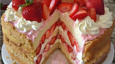A beautifully assembled strawberry shortcake on a serving plate, layered with lush whipped cream and fresh strawberries, set against a bright, airy kitchen background, evoking a sense of homemade luxury.