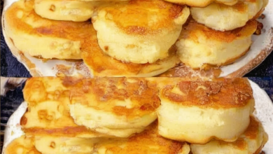 Close-up of golden brown yogurt pancakes topped with sautéed apple slices, garnished with a sprinkle of cinnamon, and served on a white plate.