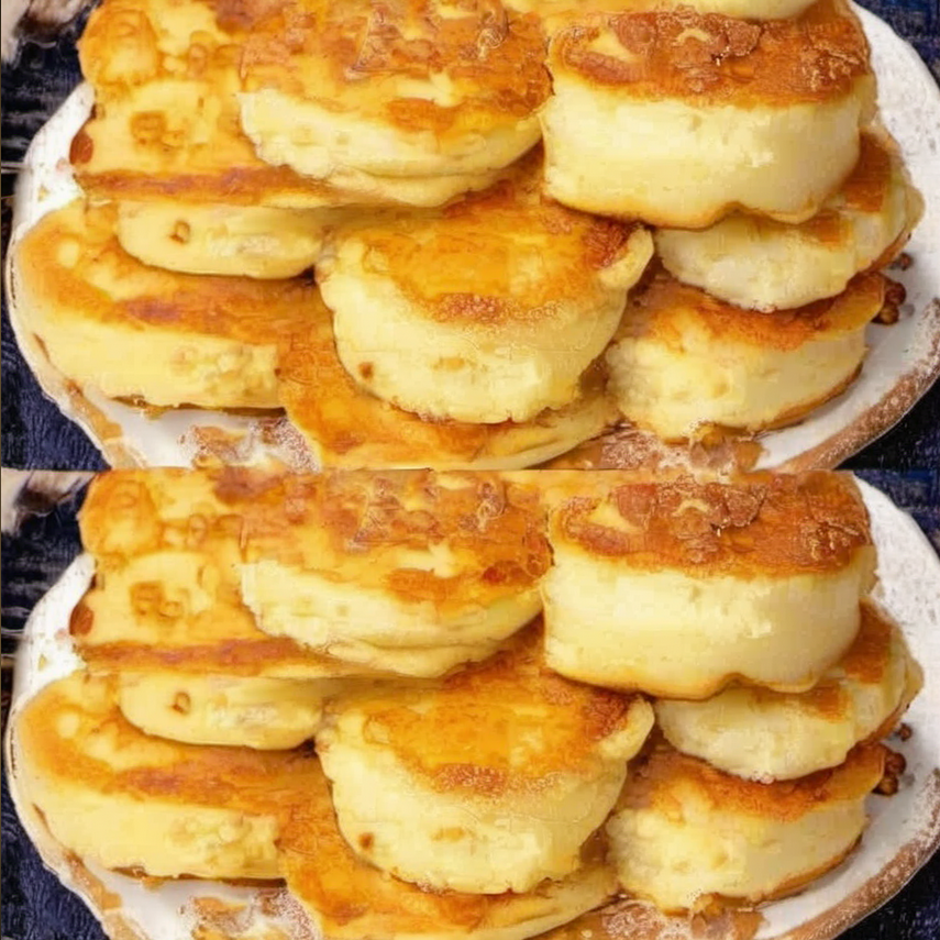 Close-up of golden brown yogurt pancakes topped with sautéed apple slices, garnished with a sprinkle of cinnamon, and served on a white plate.