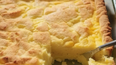 Close-up of a freshly baked Lemon Cream Cheese Dump Cake with a golden-brown top, showing hints of cream cheese and lemon filling, garnished with a sprig of mint.