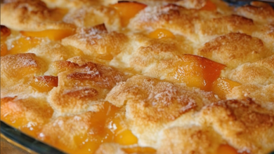 A delicious slice of old-fashioned oven-baked peach cobbler served warm with a scoop of vanilla ice cream