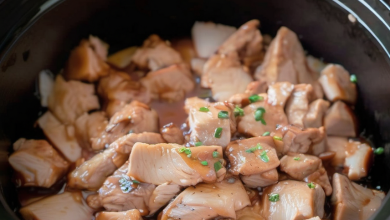 A plate of juicy slow cooker teriyaki chicken garnished with green onions, served with steamed vegetables and warm rice.