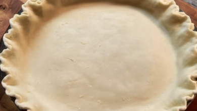 A perfectly golden, flaky pie crust filled with sweet apple slices, sitting on a rustic wooden table.