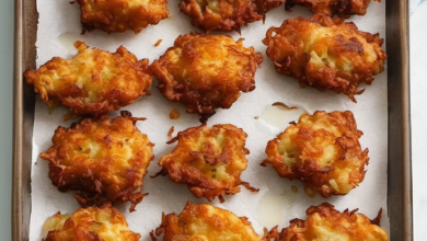 Golden and crispy Amish Onion Fritters served on a plate with a side of dipping sauce.