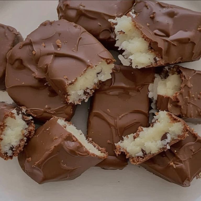 Homemade chocolate coconut bars with a rich chocolate coating and a sweet coconut filling, displayed on a parchment-lined baking sheet