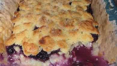 A slice of golden brown Mountain Cobbler with juicy blackberries, served warm with a dollop of whipped cream