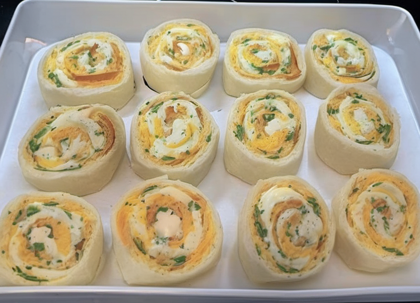 Golden brown breakfast rolls filled with sausage, egg, and cheese, topped with creamy sausage gravy, served on a white plate