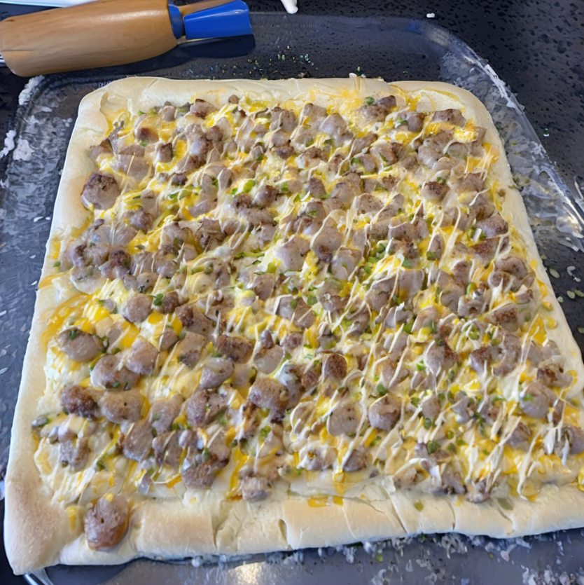 Golden brown breakfast rolls filled with sausage, egg, and cheese, topped with creamy sausage gravy, served on a white plate