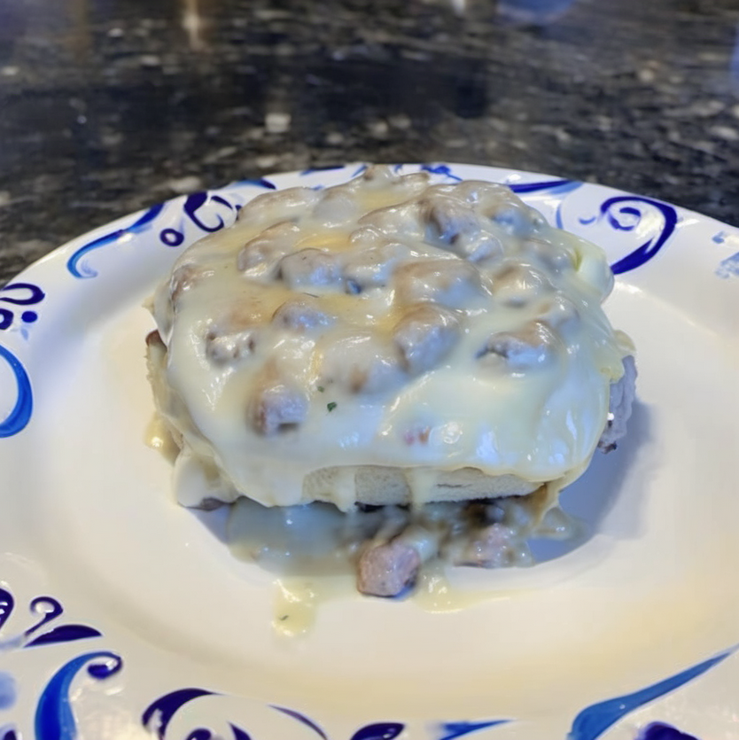 Golden brown breakfast rolls filled with sausage, egg, and cheese, topped with creamy sausage gravy, served on a white plate