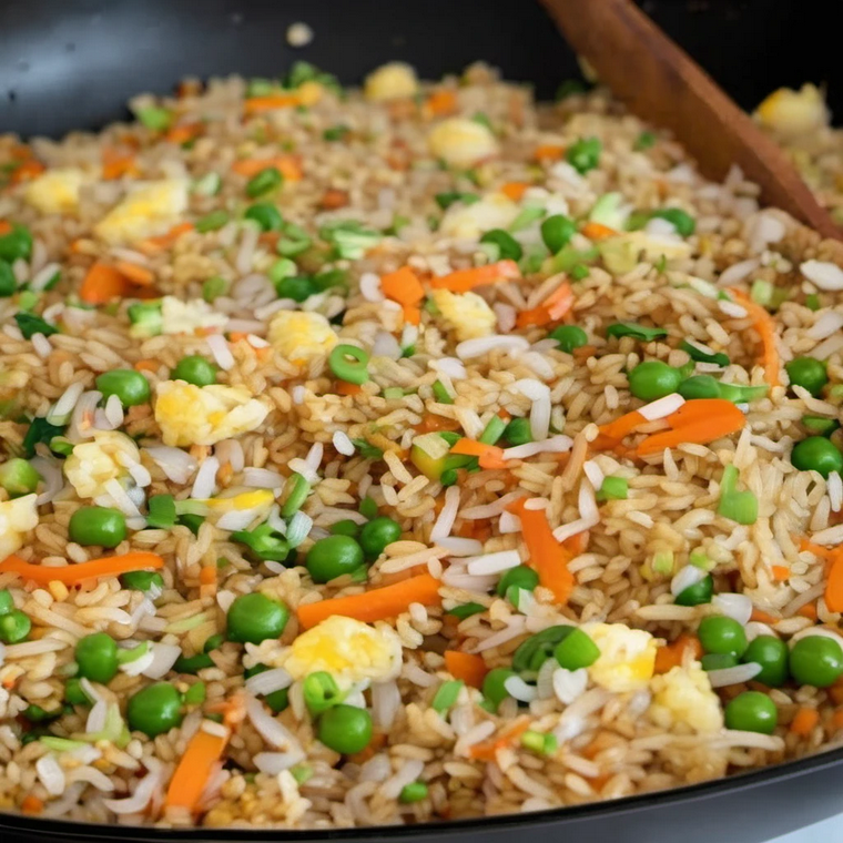 Preparing homemade fried rice with eggs, carrots, and onions in a large wok