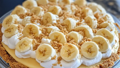 A homemade banana cream pie with graham cracker crust, topped with fresh bananas and whipped cream.