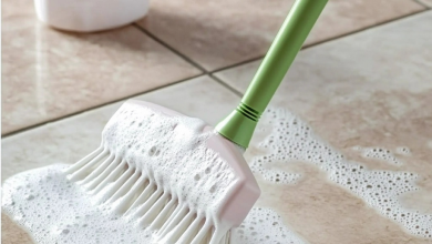 A spray bottle filled with homemade vinegar floor cleaner next to a mop on a clean, shiny wooden floor