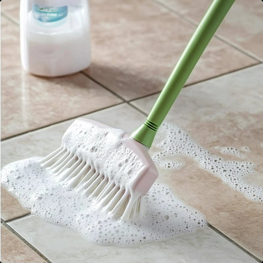 A spray bottle filled with homemade vinegar floor cleaner next to a mop on a clean, shiny wooden floor