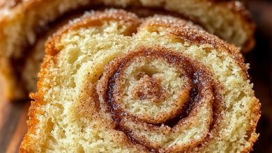 Freshly baked Amish Cinnamon Bread with a golden crust, topped with a swirl of cinnamon sugar, served on a rustic wooden board