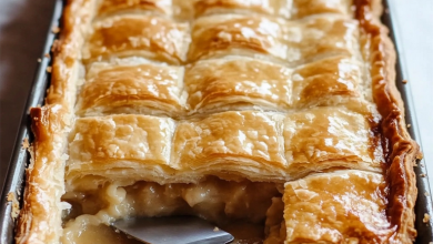 A large apple slab pie cooling on a rack, with a golden-brown crust and bubbling apple filling