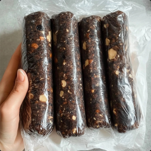 A sliced chocolate salami coated in powdered sugar, revealing pieces of cookies and walnuts inside. Perfect for parties or holiday gatherings.