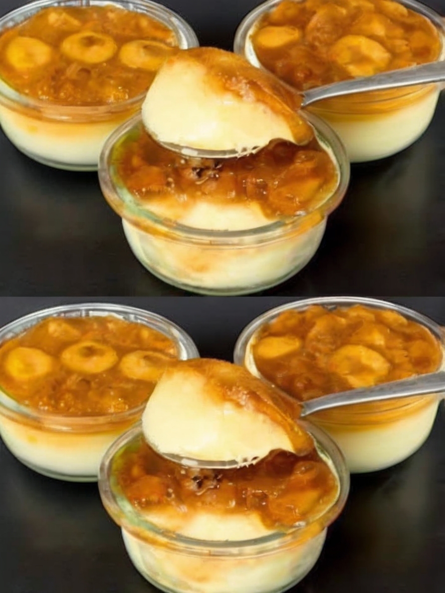 A beautifully layered Banana Foster Dessert in a glass cup, with creamy banana pudding on the bottom, topped with golden-brown caramelized bananas, glistening with a rich, syrupy sauce. Fresh banana slices and a hint of caramel sauce drizzle down the sides, creating a tempting and elegant presentation. The dessert is set against a cozy, rustic background with whole bananas, a small pitcher of caramel sauce, and a sprinkle of cinnamon, making it look inviting and delicious.