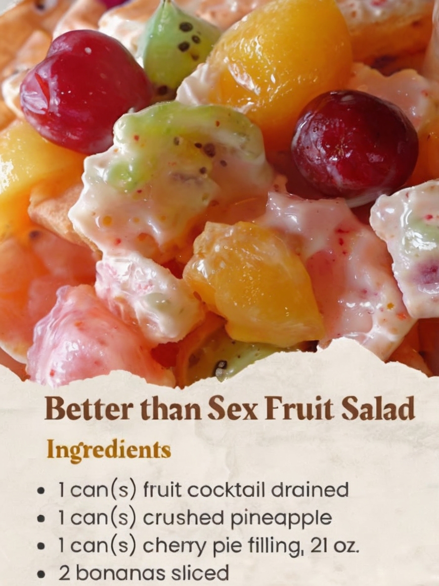 A vibrant bowl of Better Than Sex Fruit Salad filled with pineapple chunks, cherry pie filling, bananas, and marshmallows, topped with a dollop of whipped cream and garnished with fresh mint