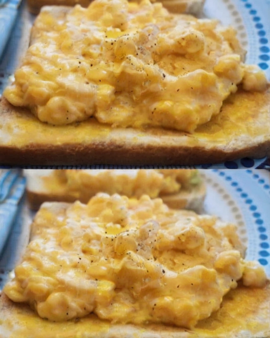 A plate of perfectly cooked scrambled eggs, garnished with fresh chives, served alongside avocado slices and whole-grain toast. The eggs should appear creamy and fluffy, with steam rising for a fresh-out-of-the-pan effect.