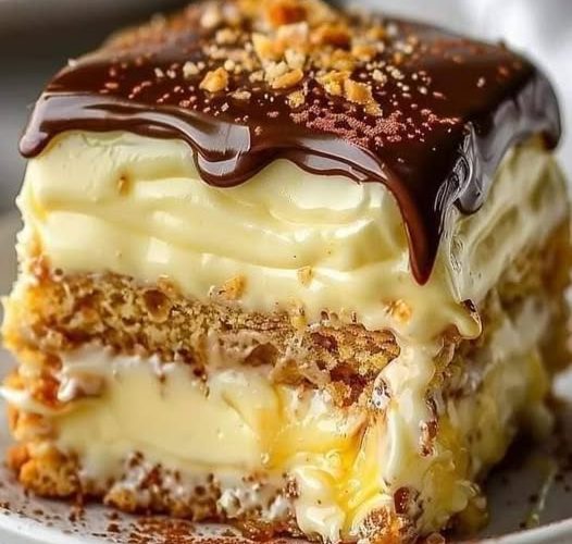 No-Bake Chocolate Eclair Cake—a chilled, creamy classic layered with graham crackers, silky vanilla pudding, whipped topping, and a rich chocolate glaze.