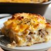 A comforting breakfast casserole featuring fluffy biscuits, savory sausage gravy, crispy hashbrowns, and melted cheddar cheese.