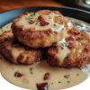 juicy, golden-fried pork chops with that perfect crispy crust, smothered in creamy, savory bacon gravy made right in the same skillet