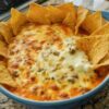 The legendary party dip that causes actual crowds to form: creamy refried beans mixed with cream cheese and sour cream, topped with seasoned ground beef and melted cheese, baked until bubbling and golden. Feeds 8-10 people and disappears every single time. Perfect for game day, potlucks, or any time you need to be the hero.