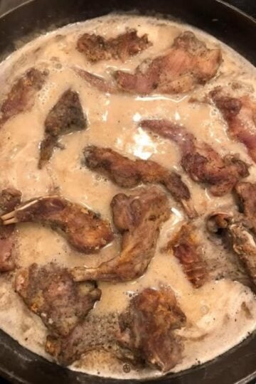 A traditional Southern hunting camp breakfast featuring fried squirrel slowly simmered in rich homemade country gravy and served over warm buttermilk biscuits.