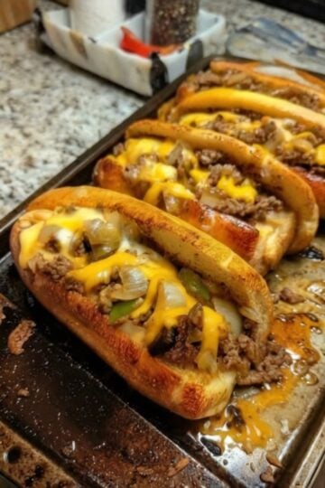 Tender shaved ribeye steak, sautéed onions and peppers, melted provolone cheese, and toasted hoagie rolls create the ultimate homemade Philly cheesesteak sandwich.