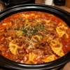 A rustic bowl of One Pot Lasagna Soup filled with seasoned ground beef, Italian sausage, tender lasagna noodles, and a rich tomato broth, topped with creamy ricotta, melted mozzarella, grated Parmesan, and fresh basil. The hearty Italian-inspired soup is served with slices of garlic bread on a wooden table, creating the perfect comforting family dinner.