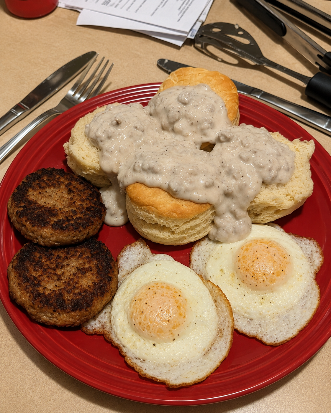 Southern biscuits and sausage gravy breakfast plate with fluffy buttermilk biscuits covered in creamy peppered sausage gravy, crispy sausage patties, and fried eggs.