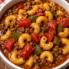Old-Fashioned Crockpot Goulash made with seasoned ground beef, tender elbow macaroni, bell peppers, sweet peas, and a rich tomato sauce, served in a rustic bowl and garnished with fresh parsley. A hearty American slow cooker comfort food perfect for family dinners and meal prep.