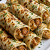 Creamy chicken ranch wraps baked golden in a 9x13 dish with seasoned ground chicken, melted cream cheese, mozzarella, ranch butter topping, and fresh parsley.