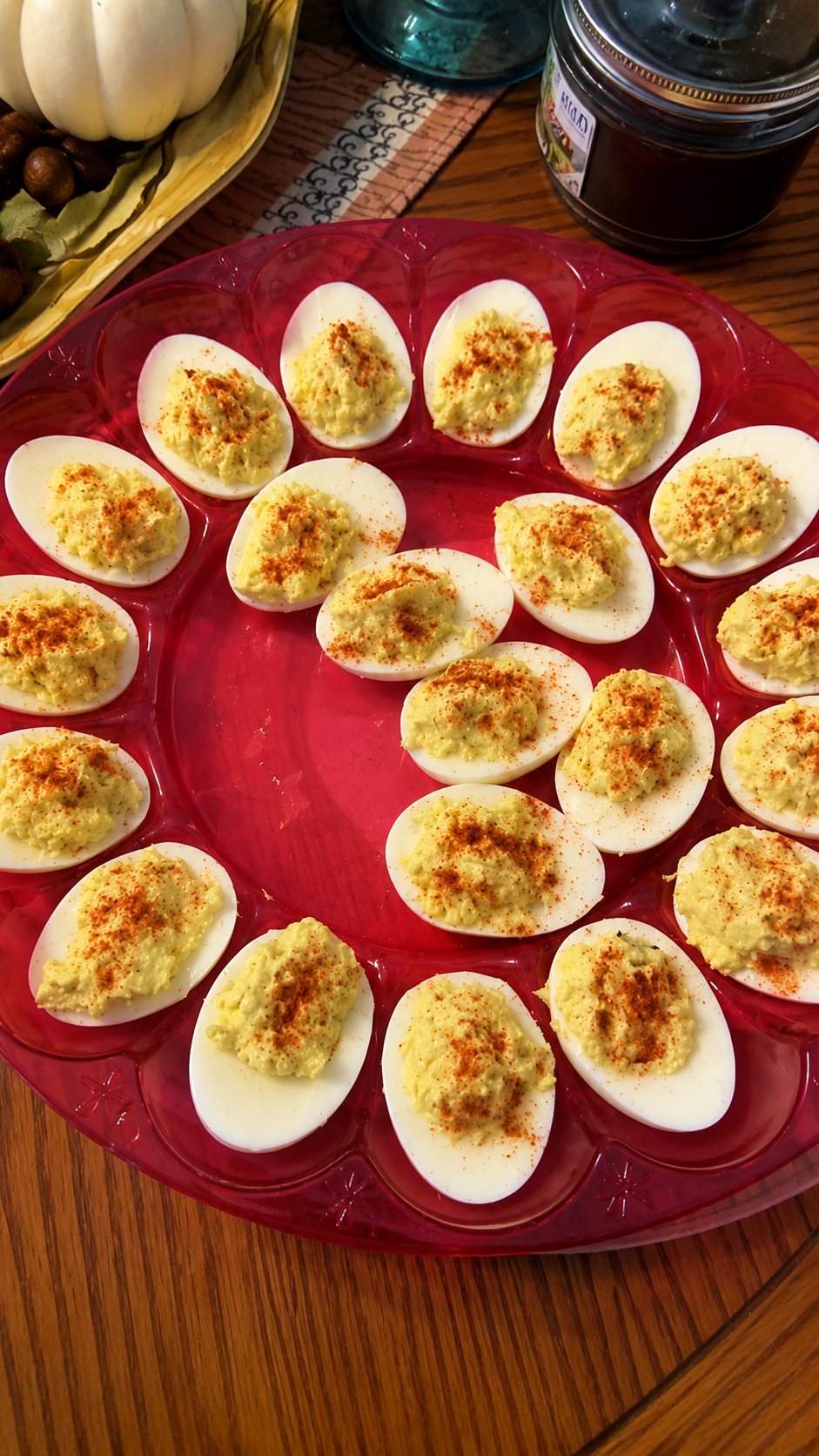 "Classic deviled eggs arranged on a red serving tray, filled with creamy seasoned yolk mixture and sprinkled with paprika for a traditional homemade appetizer