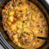 Creamy Slow Cooker Potato Bacon Soup served in a rustic bowl, loaded with tender diced potatoes, crispy bacon, and a rich, velvety broth. Garnished with shredded cheddar cheese, chopped green onions, and fresh parsley, this hearty homemade comfort food is perfect for cozy family dinners on chilly days.