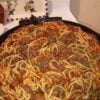 Classic homemade spaghetti topped with rich ground beef tomato sauce, garnished with fresh parsley and grated Parmesan cheese, served in a rustic bowl for a comforting American family dinner.