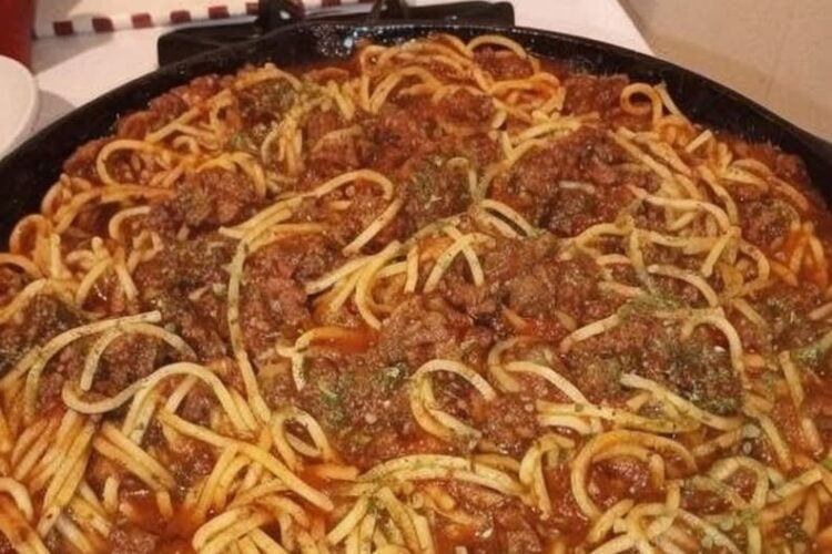 Classic homemade spaghetti topped with rich ground beef tomato sauce, garnished with fresh parsley and grated Parmesan cheese, served in a rustic bowl for a comforting American family dinner.