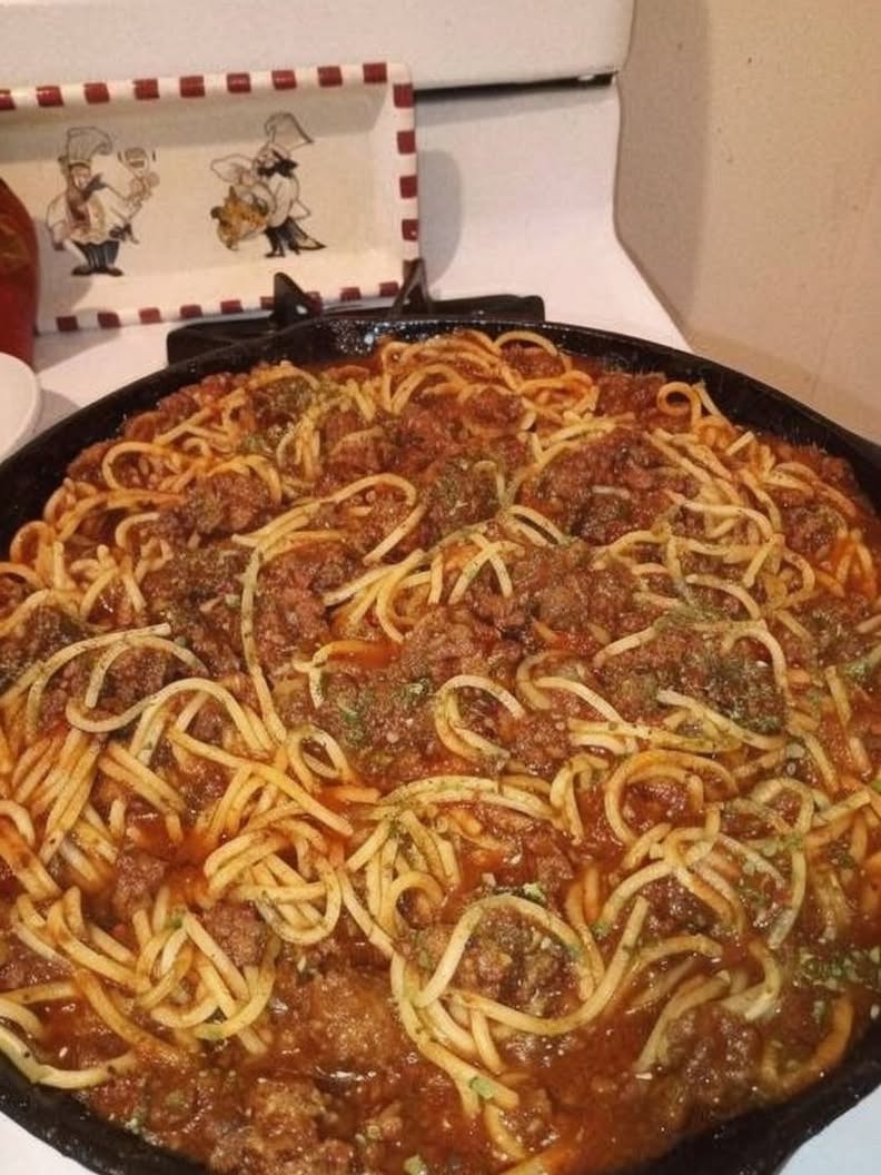 Classic homemade spaghetti topped with rich ground beef tomato sauce, garnished with fresh parsley and grated Parmesan cheese, served in a rustic bowl for a comforting American family dinner.